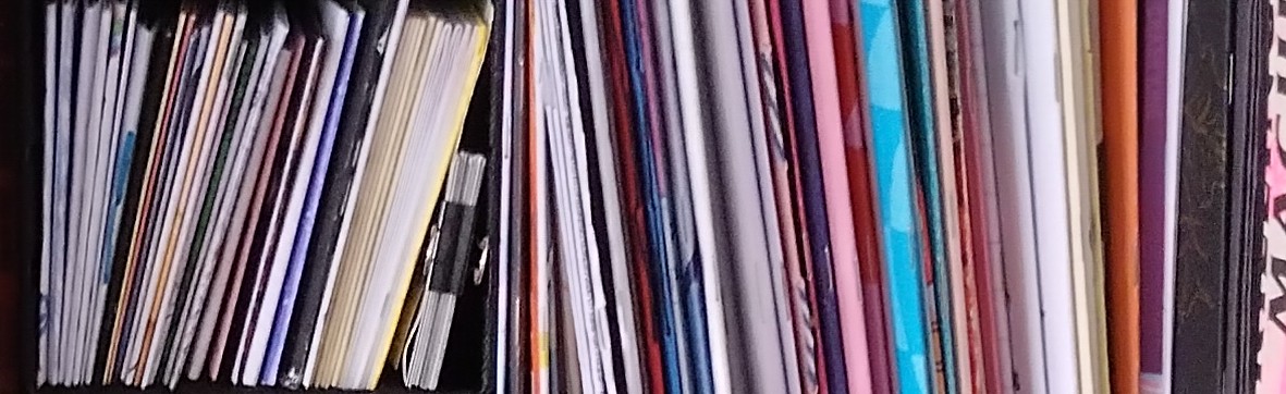 webpage banner, an image of zines on a bookshelf